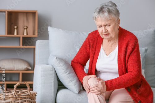 Fotomural Senior woman suffering from pain in knee at home