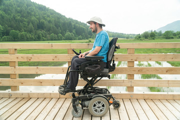 Wall Mural - disabled Young man in electric wheelchair on a boardwalk enjoying his freedom and observing nature