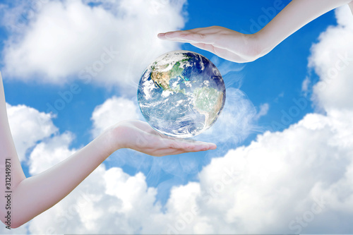 An arm holding the earth into copy space of blue sky. Concept save the earth with your hand.Elements of this image furnished by NASA .