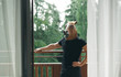 © bodnarphoto - Athletic man in horse mask standing on balcony in apartment overlooking forest, looking into camera. Man stands on a balcony in a hotel outside the city in the woods.