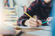 © panitan - high school,university student study.hands holding pencil writing paper answer sheet.sitting lecture chair taking final exam