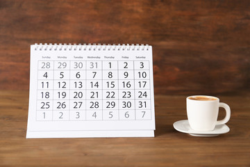 Poster - Calendar and cup of coffee on wooden table