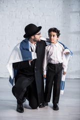 Wall Mural - smiling jewish father and cute son with flag of israel looking at each other