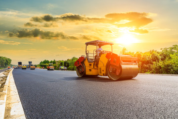 Construction site is laying new asphalt road pavement,road construction workers and road construction machinery scene.