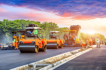 Construction site is laying new asphalt road pavement,road construction workers and road construction machinery scene.