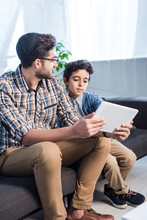 Jewish Father And Son Using Digital Tablet In Apartment