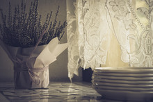 Composition On A Windowsill In A Restaurant With A Stack Of White Plates And Heather Flowers In A Basket Decorated With Thin Paper.