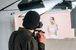 © LIGHTFIELD STUDIOS - Back view of cameraman working with female model in photo studio
