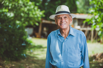 Portrait of smiling beautiful older male farmer. Elderly man at farm in summer day. Gardening activity. Brazilian elderly man.