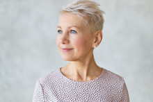 Close Up Studio Image Of Beautiful Attractive Middle Aged European Lady With Stylish Haircut And Neat Make Up Looking Away With Confident Smile Posing Isolated Against Marbled Wall Background