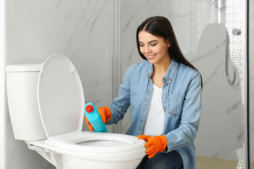 Poster - Young woman cleaning toilet bowl in bathroom