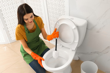 Sticker - Young woman cleaning toilet bowl in bathroom