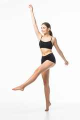 Wall Mural - Full length portrait of a young brunette woman with perfect body raised hands in black sport lingerie posing and looking away isolated on a white background