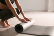 © New Africa - Woman rolling yoga mat in studio, closeup
