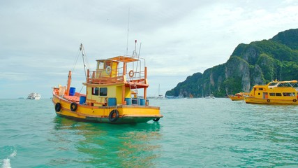 Yellow tour boat on turquoise waters off the coast of Phi Phi island, Thailand.