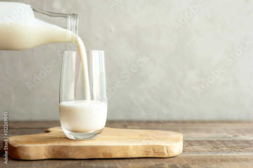 Fotografía Kefir, milk or Turkish Ayran drink are poured into a glass cup from a bottle