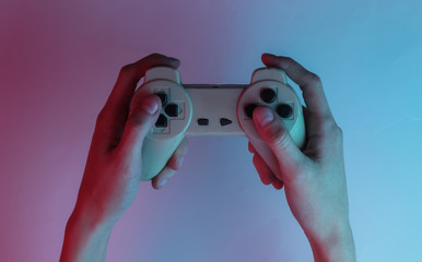 Gamer concept. Hand holds gamepad. Creative pop art pink blue neon color. Trendy gradient illumination. Night light