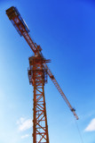 Fototapeta  - Yellow tower cranes at construction site. Construction site with tower cranes against blue sky. Crane and building construction site at sunset. Selected focus