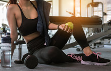 Woman Holding Apple After Fitness Exercise At Gym. Healthy And Lifestyle Concept.