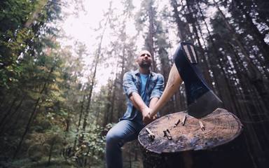 Male lumberjack in the forest. A professional woodcutter inspects trees for felling.