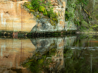 Wall Mural - a landscape with a steep river and caves on a sandstone cliff