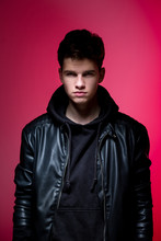 Cute Brutal Man In Black Leather Jacket Model Style. Portrait Of A Handsome Guy On Pink Studio Background. Man In Black Jacket. Young Fashion Man In Leather Jacket On A Pink Background