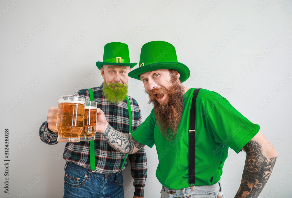 Bearded men with glasses of beer on light background. St. Patrick's Day celebration