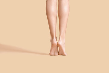 Legs of beautiful young woman on color background