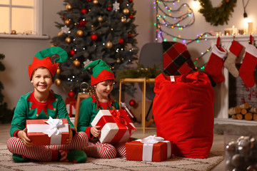 Sticker - Little children in costume of elf and with gifts in room decorated for Christmas