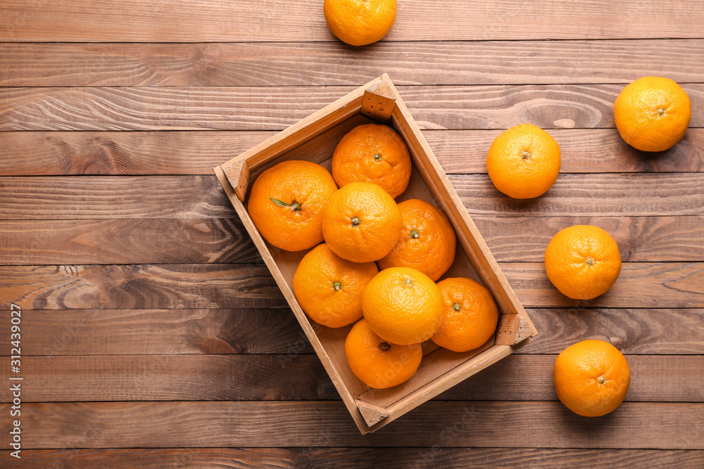 Box with sweet tangerines on wooden background