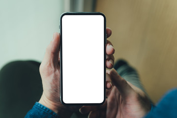 Mockup image blank white screen cell phone.man hand holding texting using mobile on sofa at coffee shop.background empty space for advertise text.people contact marketing business,technology