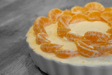 Orange Cheesecake With Cream And Orange Peel Topped With Satsuma Segments In A White Dish.  With Selective Colour