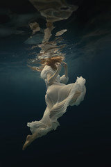 Wall Mural - Girl in a beautiful dress swims underwater