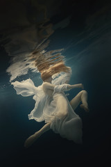 Girl in a beautiful dress swims underwater