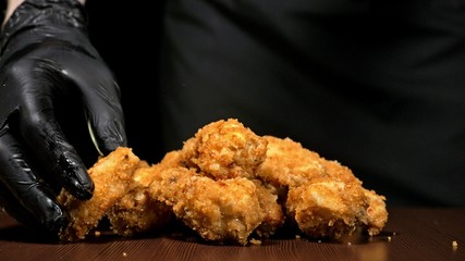 Cool beautiful fresh juicy cooked chicken wings in breading. Buffalo wings spread on food white plate in table. Very tasty and beautiful. Cooking with deep fryer fry machine.