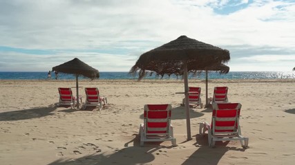 Wall Mural - Tourists walk along the beach with sun beds and umbrellas overlooking the sea.