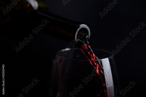 Cuadros en Lienzo Red wine pouring in wine glass over black background