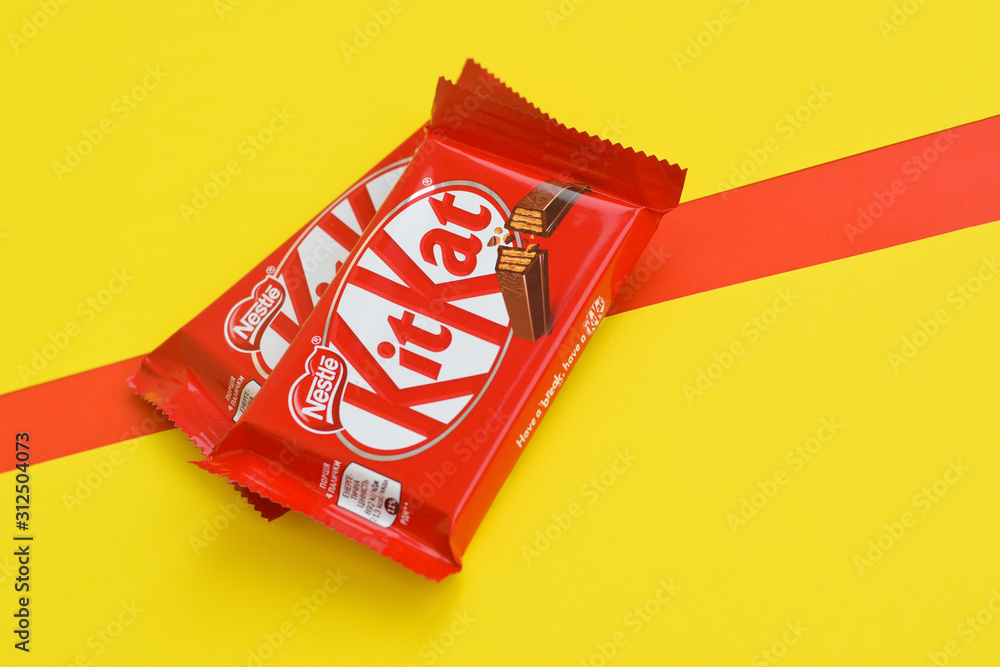 Kit Kat chocolate bars in red wrapping lies on yellow and red ...