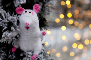 Wall Mural - New Year card with white knitted toy rat on background of snow covered fir branches and golden lights. Chinese Year of Rat, Zodiac symbol 2020