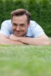 © MDBPIXS - Portrait of smiling young man lying on grass in park