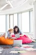 © MDBPIXS - Businesswomen using tablet PC while relaxing on beanbag chairs at creative office