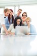 © MDBPIXS - Business colleagues using laptop at desk in creative office