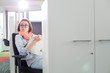 © MDBPIXS - Businesswoman holding notepad while sitting on chair at creative office