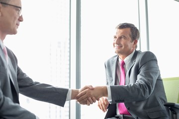 Wall Mural - Mature businessmen shaking hands in office