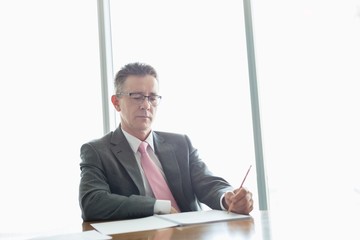 Wall Mural - Mature businessman writing on book at table in office