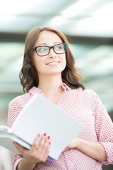 Wall Mural - Smiling woman looking away while holding book outdoors