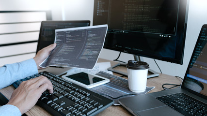Wall Mural - programmer working on computer in it office typing data coding in software and checking code on comp