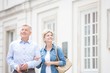 © MDBPIXS - Happy middle-aged couple standing with arm in arm outside building