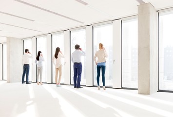  Full length rear view of business people using mobile phone in new office