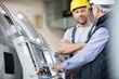 © MDBPIXS - Mid adult manual worker having discussion with colleague by machinery in industry